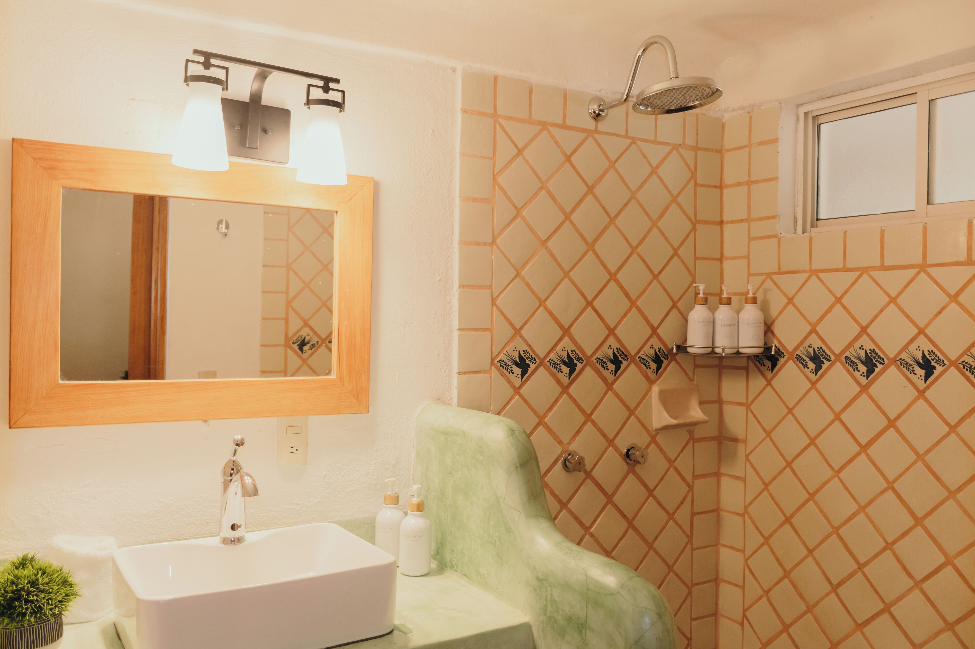 Un baño con lavamanos, espejo, ducha y azulejos decorativos.