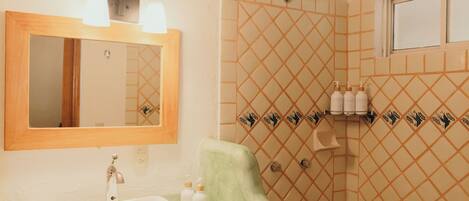 Un baño con lavamanos, espejo, ducha y azulejos decorativos.