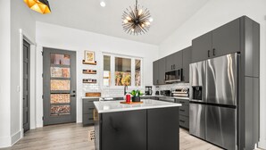 A modern kitchen with a central island, stainless steel appliances, and a black cabinetry design. - Modern Mountain Mansion with stunning view (Lake Lure)