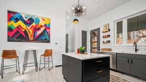 A modern kitchen with black cabinets, a white countertop, and a colorful abstract painting on the wall. - Modern Mountain Mansion with stunning view (Lake Lure)