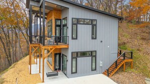 A modern two-story cabin with a balcony, large windows, and a wooden deck. - Modern Mountain Mansion with stunning view (Lake Lure)