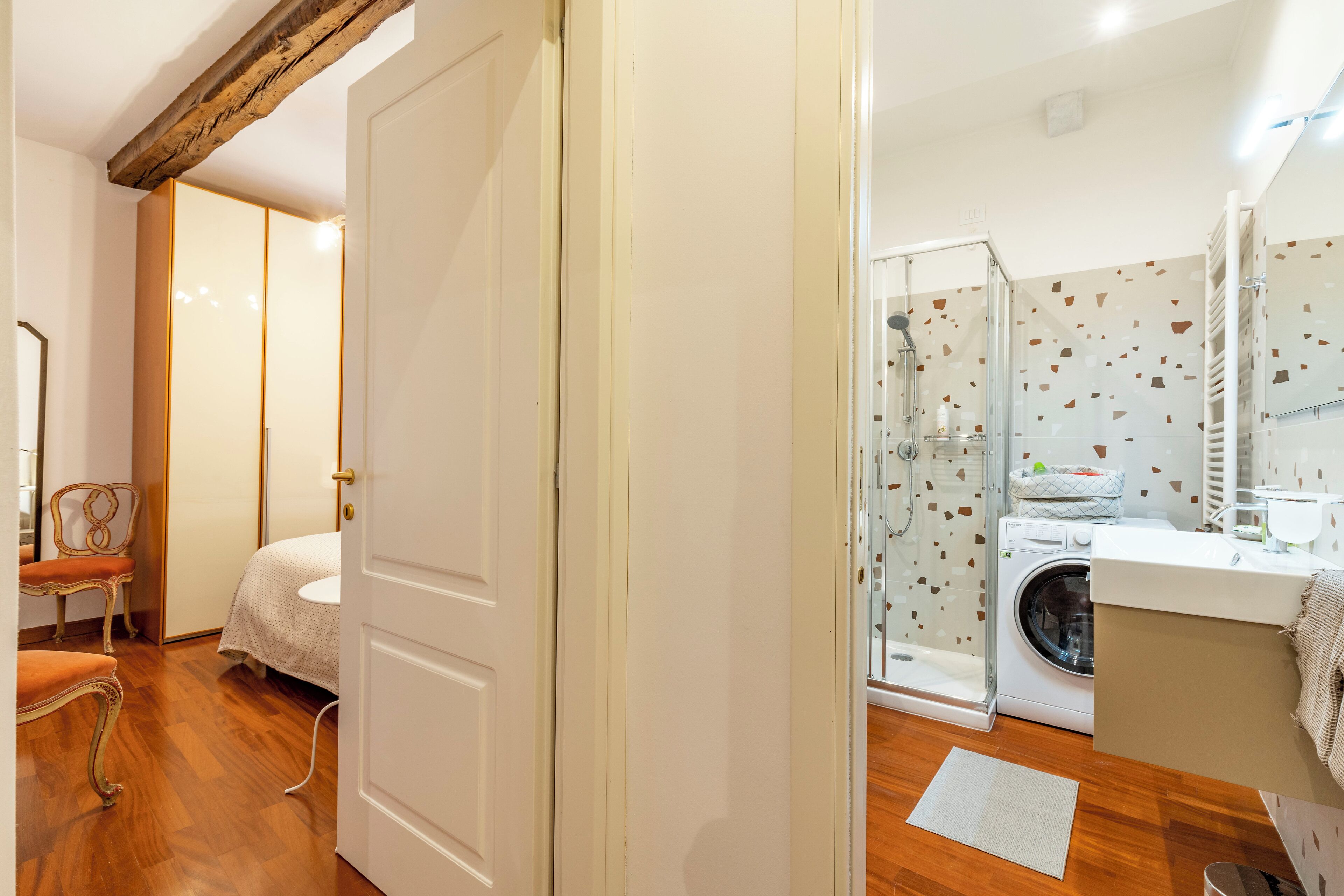 A bedroom with a wooden floor, a bed, a chair, and a wardrobe.