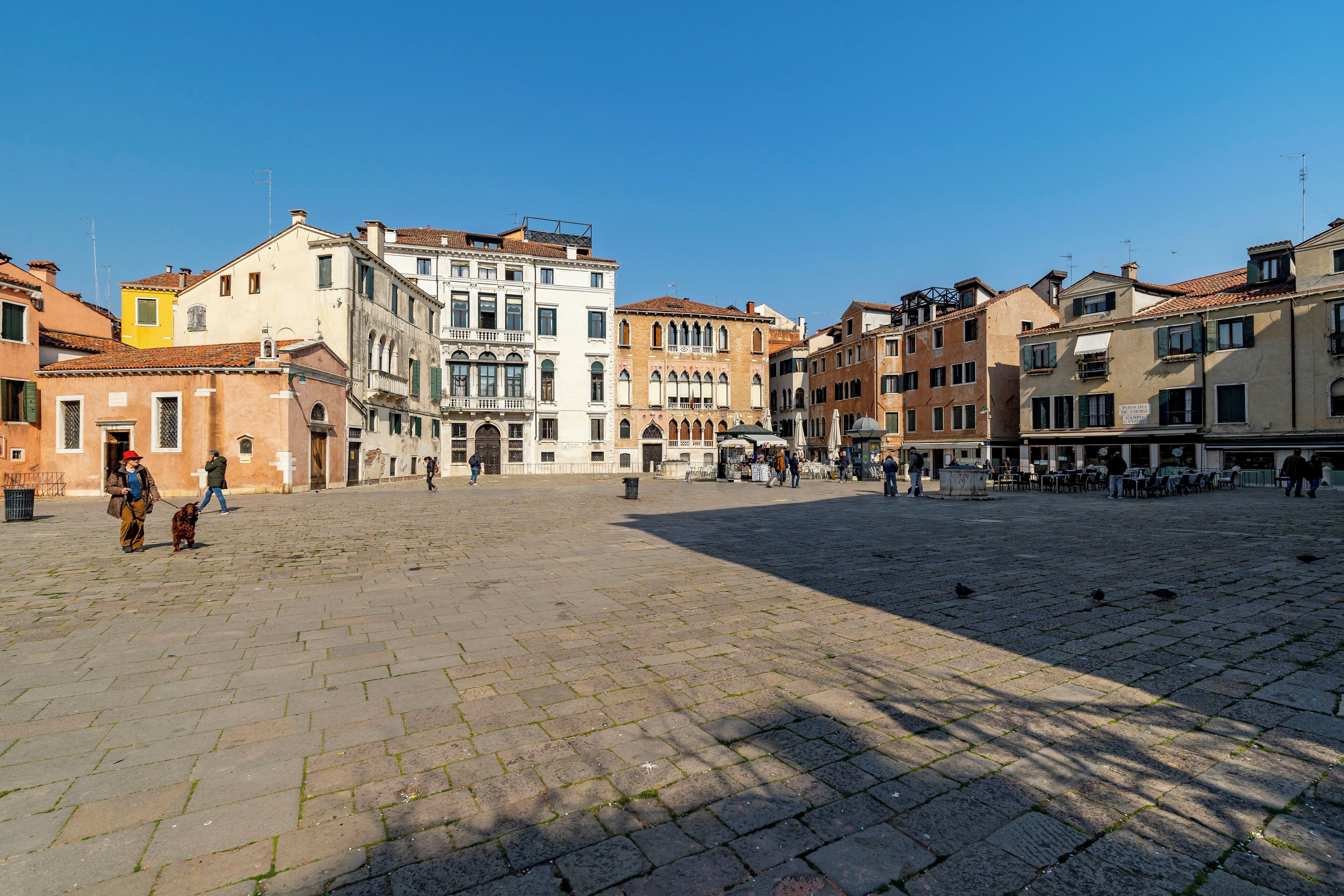 A spacious public square with historic buildings, cobblestone paving, and outdoor seating areas.