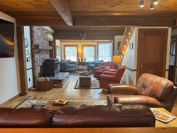 A cozy living room with a fireplace, leather sofas, and a wooden ceiling.