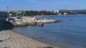 A coastal area with a rocky breakwater, calm water, and a distant view of buildings and hills. - Apartment Paradiso for up to 4 People with Wi-Fi, Air Conditioning and Washing Machine (Krk)