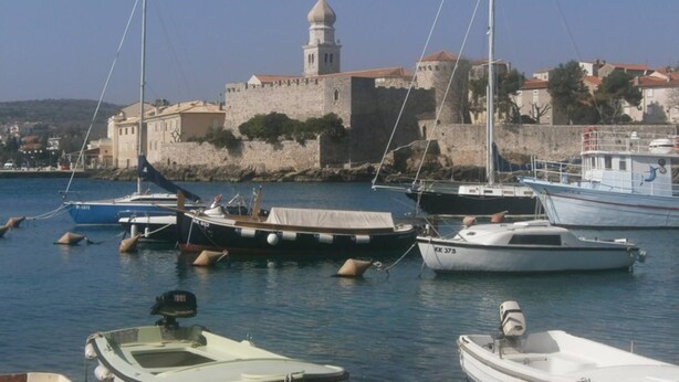A harbor with boats docked, a stone fort with a tower, and buildings in the background. - Apartment Paradiso for up to 4 People with Wi-Fi, Air Conditioning and Washing Machine (Krk)