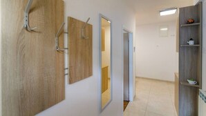 A hallway with wooden paneling, a mirror, and a shelf with a small plant. - Apartment Paradiso for up to 4 People with Wi-Fi, Air Conditioning and Washing Machine (Krk)
