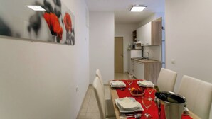 A modern dining area with a red tablecloth, white chairs, and a wine bottle. - Apartment Paradiso for up to 4 People with Wi-Fi, Air Conditioning and Washing Machine (Krk)