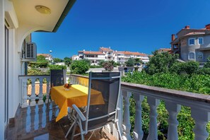 A balcony with a table and chairs, overlooking a residential area with houses and greenery. - Lovely Studio Paradiso °2 in Krk with Air Conditioning, Wi-Fi, Shared Grill (Krk)