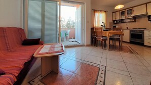 A compact living space with a sofa, a small table, a dining area, and a kitchen. - Ground floor Apartment Tihana with washing machine for up to 4 Guests (Krk)