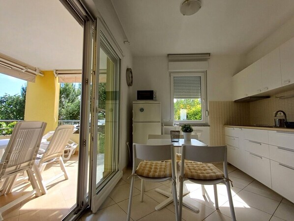 Una cocina compacta con comedor, refrigerador y ventana con persianas.