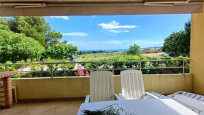 A balcony with a table set for two, overlooking a garden and distant landscape.
