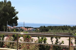 Enjoy breathtaking views of the sea and surrounding landscape from this balcony, surrounded by lush plants and flowers.