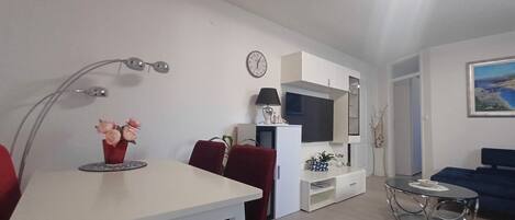 A modern living room with a dining table, red chairs, a TV, and a sofa.