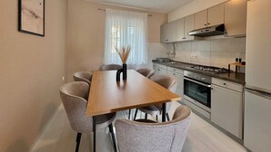 A compact kitchen with a dining table, chairs, and a modern stove. - Apartment DiSente °1 in Krk Family-friendly, Close to the center, Doga allowed (Krk)