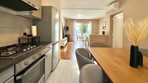 A modern kitchen with a stove, oven, and a dining area with a table and chairs. - Apartment DiSente °1 in Krk Family-friendly, Close to the center, Doga allowed (Krk)