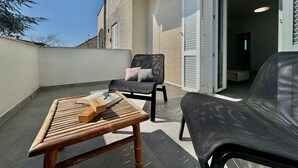 A balcony with a wooden table, two chairs, and a book.