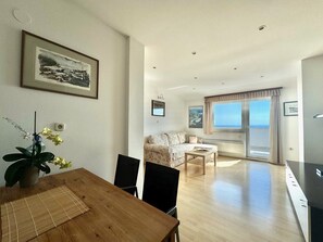 Un salon moderne comprenant un coin repas, un canapé, une table basse et une vue sur la mer.