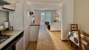 A compact kitchen with a central island, a dining area with a table and chairs, and a view through a doorway to a balcony. - Apartment DiSente °2 in Krk, family-friendly, close to the center, pets allowed, sea view (Krk)