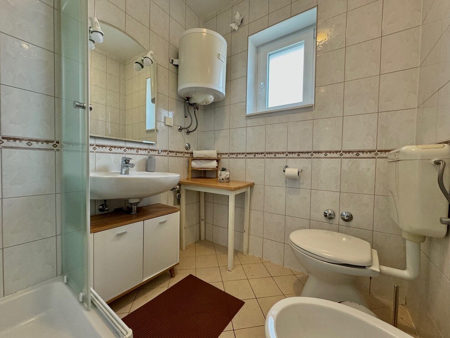 Une salle de bain avec une baignoire, des toilettes, un lavabo et une fenêtre.