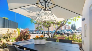 An outdoor patio with a table and chairs, a large umbrella, and potted plants. - Spacious Ground floor Apartment LiJan °1 with Two Bedrooms (Krk)