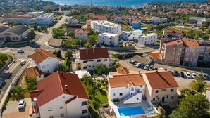 A coastal residential area with white buildings, a swimming pool, and a view of the sea. - Spacious Ground floor Apartment LiJan °1 with Two Bedrooms (Krk)