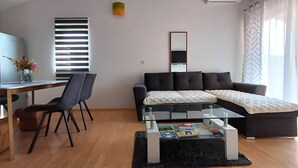 A modern living room with a sofa, a glass coffee table, a TV, and a desk with a chair. - Family-friendly Apartment Samira °4 in Krk with Air Conditioning, Parking and WiFi (Krk)