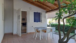 A covered patio area with a table and chairs, a wooden ceiling, and a view of a garden. - Charming Apartment Luka Near Ježevac Beach with Terrace (Krk)