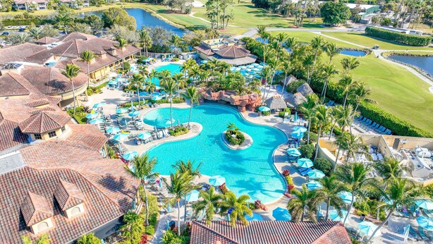 Un resort con una amplia piscina, varias zonas de descanso y un campo de golf.
