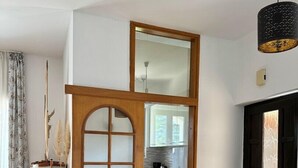A modern dining area with a wooden table, grey upholstered chairs, and a view into the kitchen. - Apartment KrisTina with pool, family friendly, WiFi, parking, pets allowed (Krk)