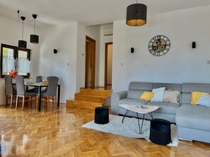 A modern living room with a grey sofa, a white coffee table, and a dining area with a table and chairs. - Apartment KrisTina with pool, family friendly, WiFi, parking, pets allowed (Krk)