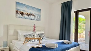 A bedroom with a bed, pillows, a tray with a teapot, a book, and a painting of a lighthouse. - Apartment KrisTina with pool, family friendly, WiFi, parking, pets allowed (Krk)