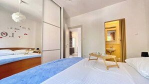 Una camera d'hotel con due letti, un piccolo tavolo con vassoio, uno specchio e una parete decorata da una frase.