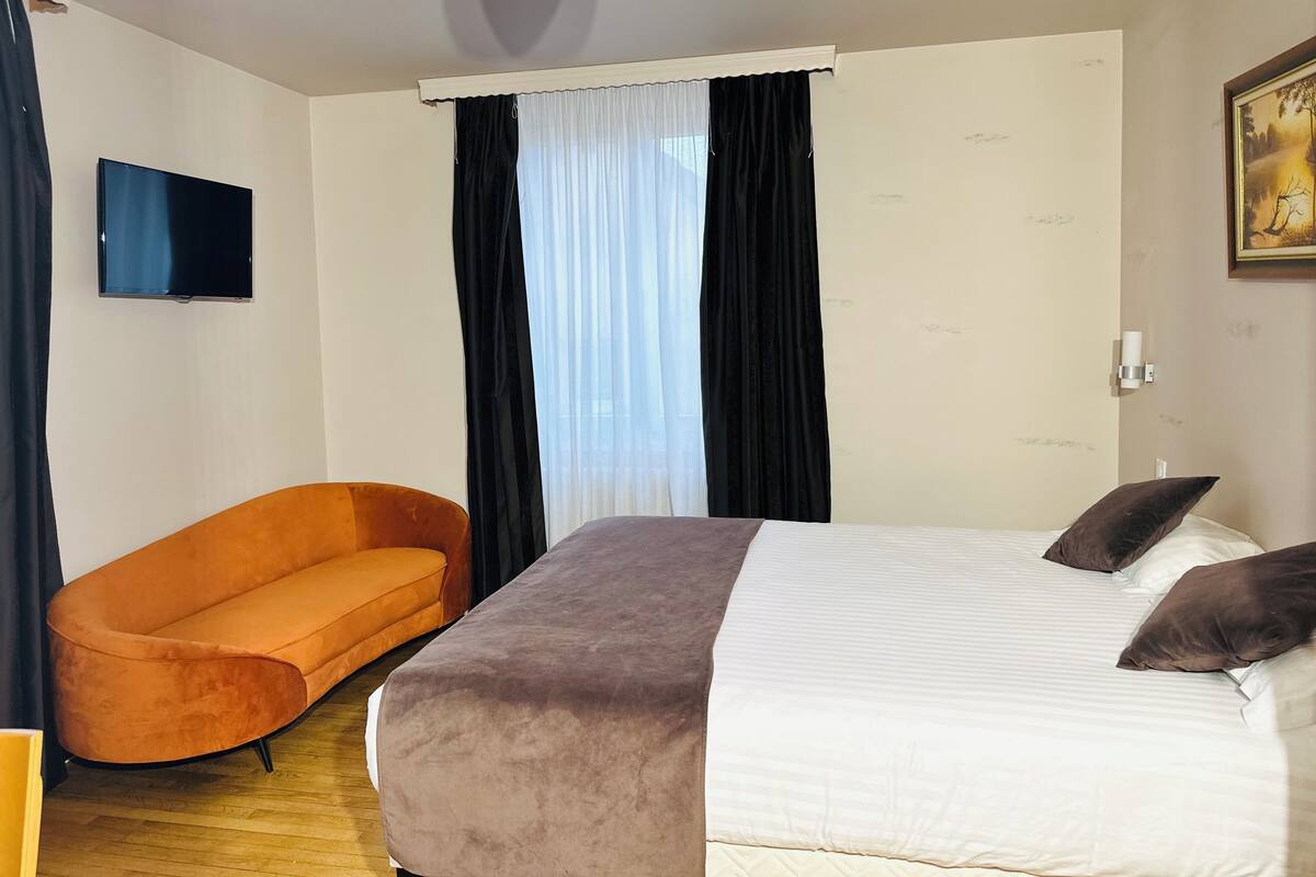 Ein Hotelzimmer mit Bett, einer Couch, einem Fernseher und einem Bild an der Wand.