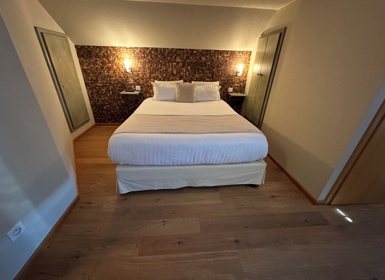 A bedroom with a large bed, a brick-patterned wall, and two bedside tables with lamps.