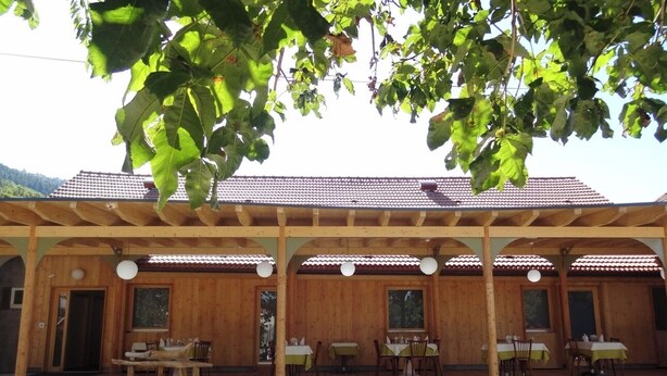 Il s’agit d’un bâtiment en bois doté d’un patio couvert, comprenant plusieurs tables et chaises.