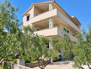 A multi-story building with balconies, surrounded by olive trees. - Family-friendly apartment Lilly with garden barbecue and trampoline (Krk)