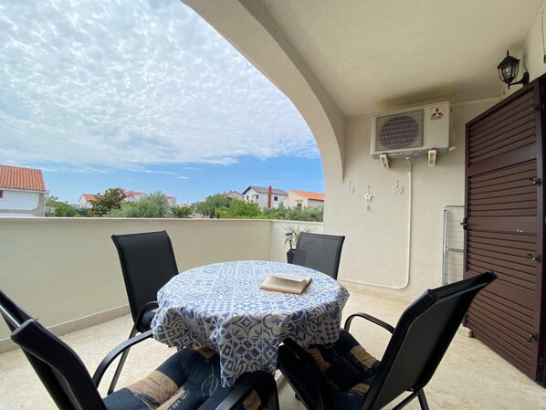 Un balcon avec une table ronde, deux chaises et un appareil de climatisation.