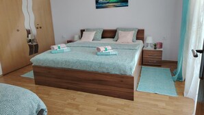 Une chambre à coucher avec un grand lit, une armoire en bois, une table de chevet et un tableau accroché au mur.