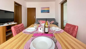 Un coin repas avec une table dressée pour quatre personnes, un téléviseur et un tableau accroché au mur.