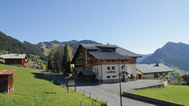 A mountain lodge with a large wooden building, a sign indicating a restaurant, and a view of the surrounding hills. - Yeti Yt76b1 SUN & View 6 Pers (Chatel)