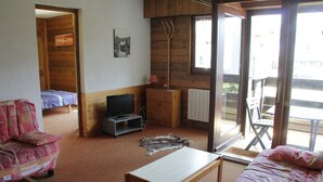 A cozy room with a bed, a wooden table, a television, and a chair. - Yeti Yt76b1 SUN & View 6 Pers (Chatel)
