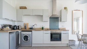 Eine kleine Küche mit Waschmaschine, Backofen und Mikrowelle.