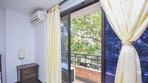 Ein Zimmer mit einer Schiebeglastür zum Balkon, einem kleinen Holzschrank und einer Klimaanlage an der Wand.