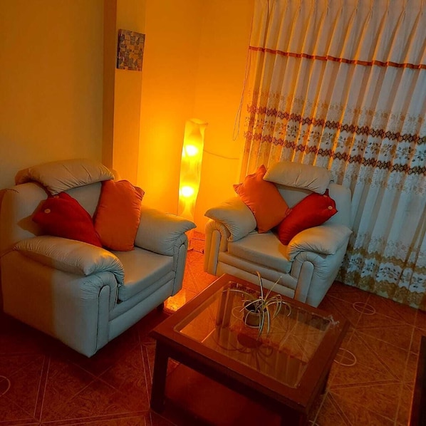Ein Wohnzimmer mit zwei Sesseln, einem Glastisch und einer Stehlampe.