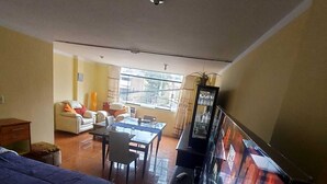 Una habitación de hotel con cama, escritorio, sillón, sofá y televisor.