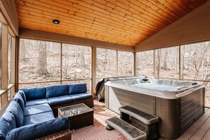 Un área de estar al aire libre con techo de madera, jacuzzi y ventanas amplias.