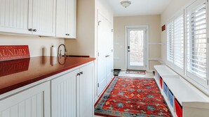 A kitchen with white cabinets, a red countertop, and a patterned rug. - Red White & WTG: Hot Tub, 5 Bedrooms! (Wintergreen Resort)