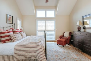 Un dormitorio con cama, una silla, cómoda y ventana.