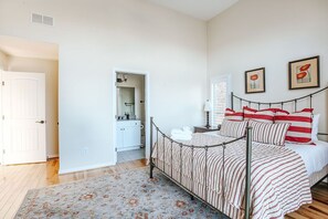 Een slaapkamer met een metalen bed, een vloerkleed met bloemenprint en een witte deur.